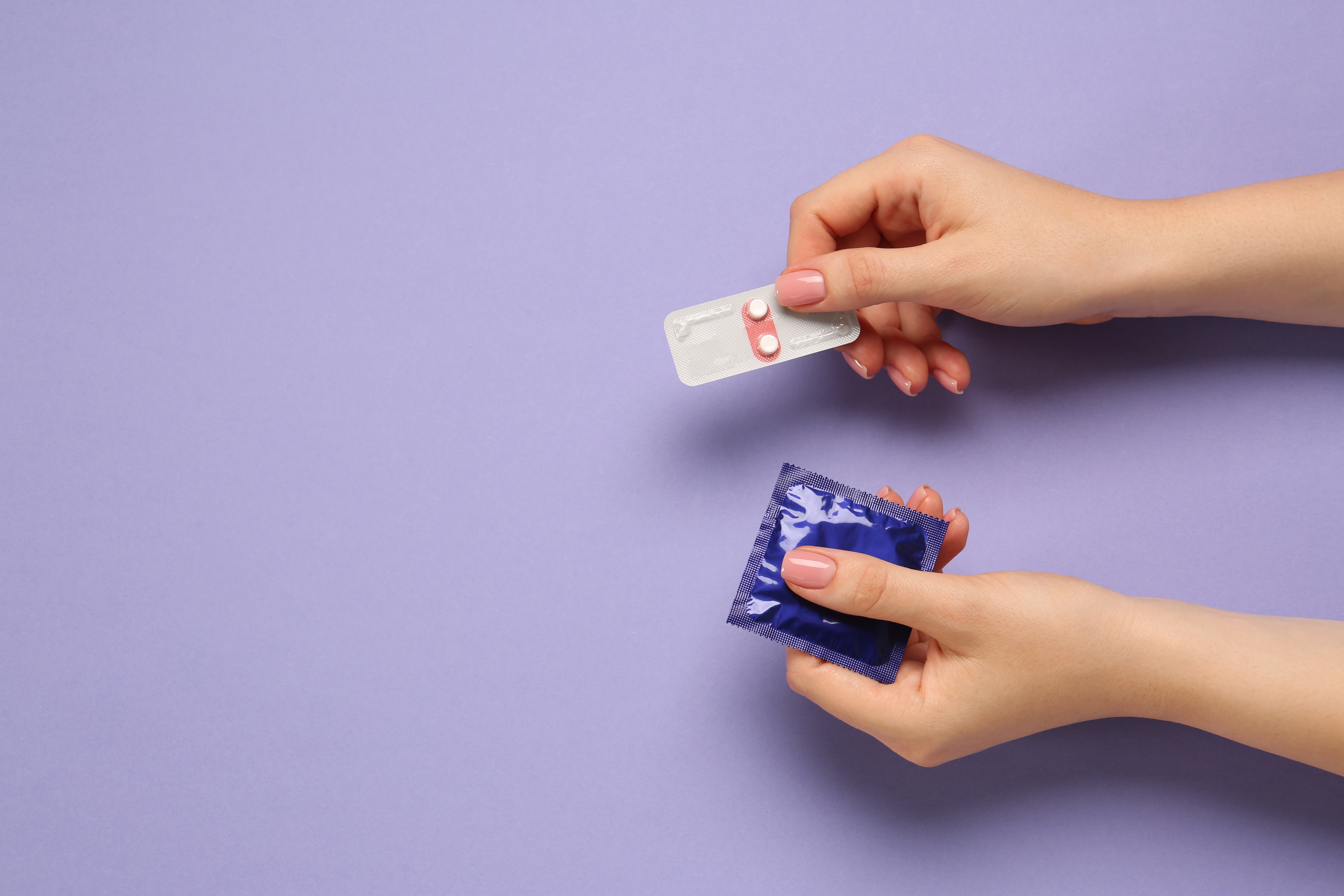 Woman,Holding,Condom,And,Contraceptive,Pills,On,Violet,Background,,Top
