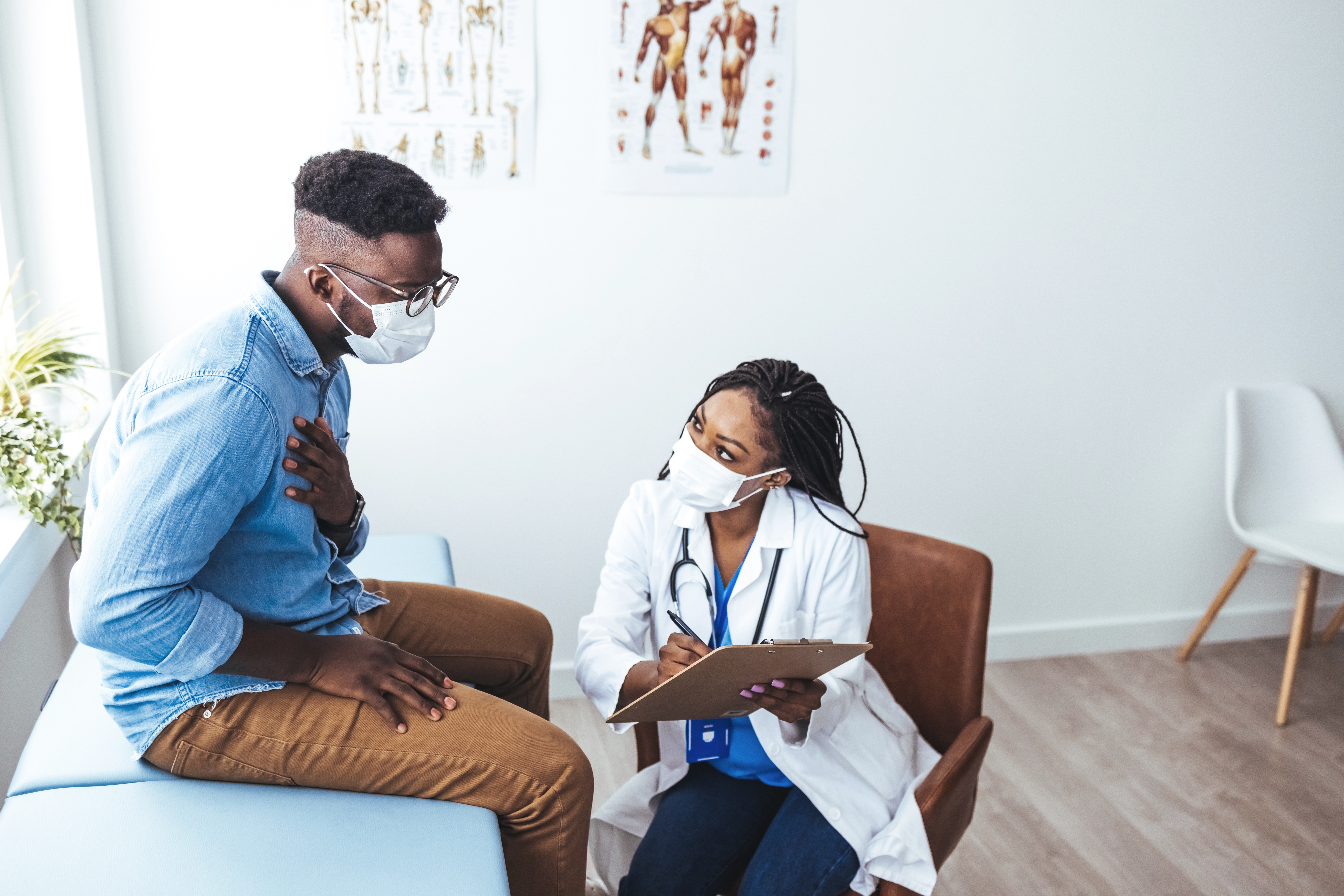 Black,Female,Doctor,Communicating,With,A,Patient,While,Wearing,Protective